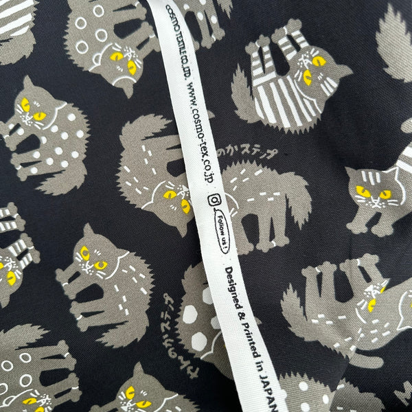 Selvage of Angry Cats Cotton Oxford Fabric in Black by Cosmo Textiles featuring black cats in a Halloween cat pose with arched backs and raised fur.