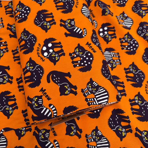 Bolt of Angry Cats Cotton Oxford Fabric in Orange by Cosmo Textiles featuring black cats in a Halloween cat pose with arched backs and raised fur.