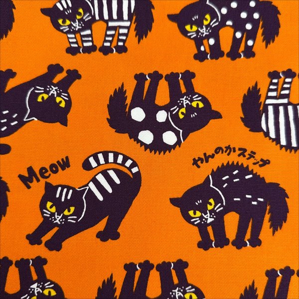 Close up of Angry Cats Cotton Oxford Fabric in Orange by Cosmo Textiles featuring black cats in a Halloween cat pose with arched backs and raised fur.