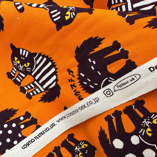 Selvage of Angry Cats Cotton Oxford Fabric in Orange by Cosmo Textiles featuring black cats in a Halloween cat pose with arched backs and raised fur.