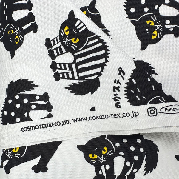 Selvage of Angry Cats Cotton Oxford Fabric in White by Cosmo Textiles featuring black cats in a Halloween cat pose with arched backs and raised fur.