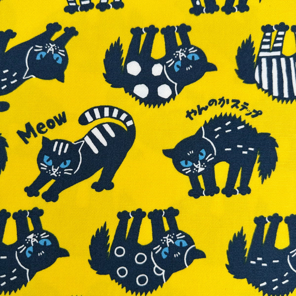 Close up of Angry Cats Cotton Oxford Fabric in Yellow by Cosmo Textiles featuring black cats in a Halloween cat pose with arched backs and raised fur.