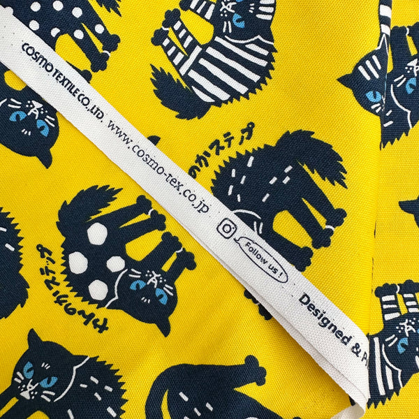 Selvage of Angry Cats Cotton Oxford Fabric in Yellow by Cosmo Textiles featuring black cats in a Halloween cat pose with arched backs and raised fur.