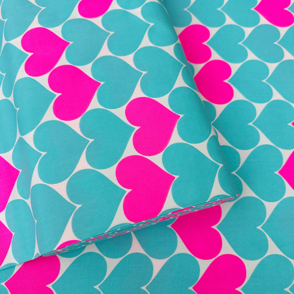 Bolt of Bon Bon Heart cotton Oxford fabric in neon pink and aqua blue featuring a large-scale heart print, imported from Japan