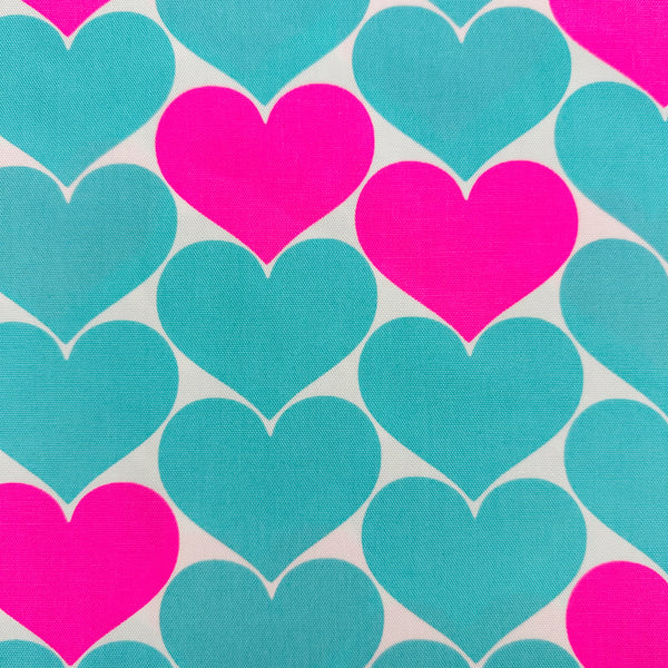 Close up of Bon Bon Heart cotton Oxford fabric in neon pink and aqua blue featuring a large-scale heart print, imported from Japan
