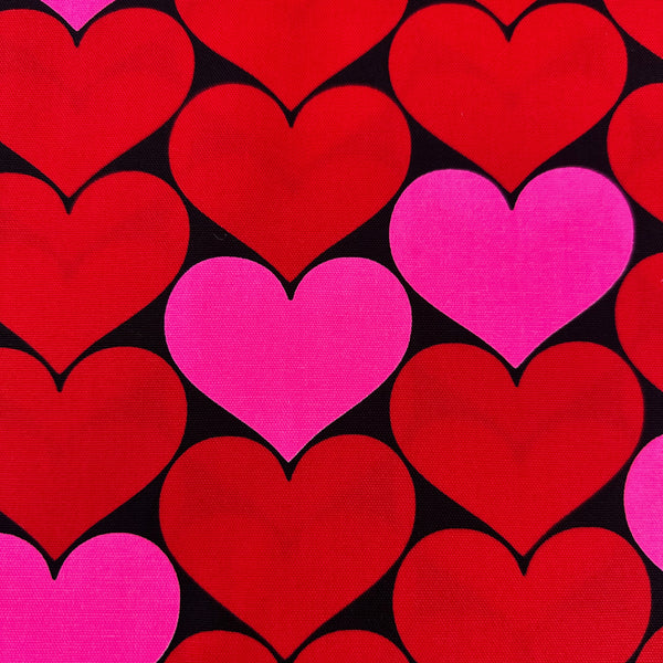 Close up of Bon Bon Heart cotton Oxford fabric in neon pink and black featuring a large-scale heart print, imported from Japan