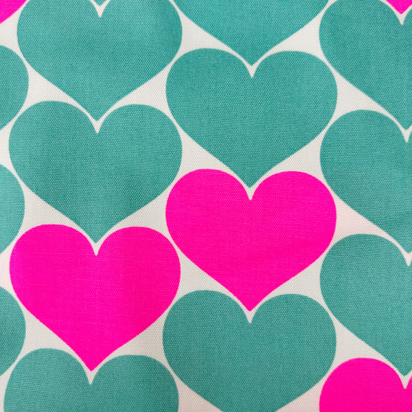 Close up of Bon Bon Heart cotton Oxford fabric in neon pink and green featuring a large-scale heart print, imported from Japan