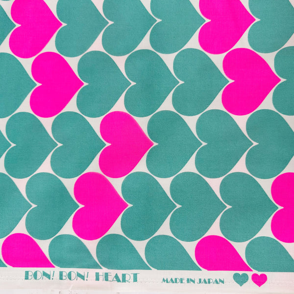Selvage of Bon Bon Heart cotton Oxford fabric in neon pink and green featuring a large-scale heart print, imported from Japan