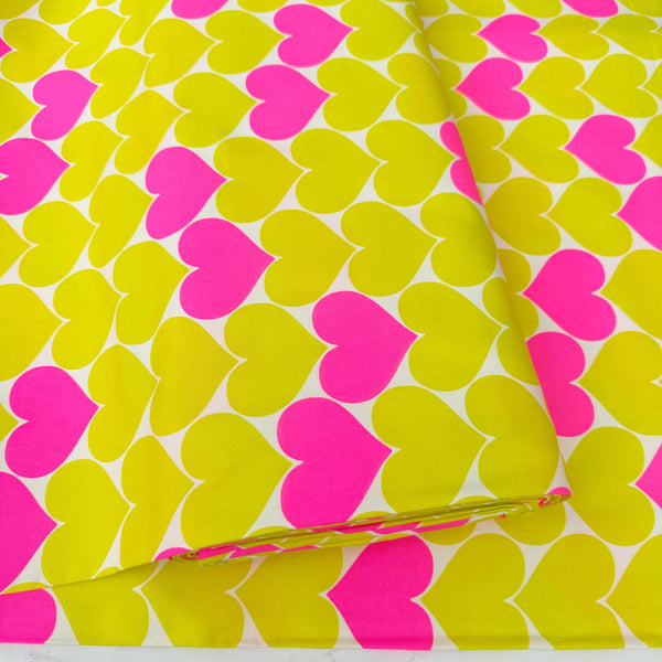Bolt of Bon Bon Heart cotton Oxford fabric in neon pink and yellow featuring a large-scale heart print, imported from Japan