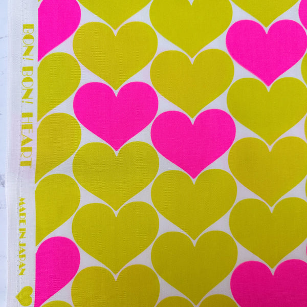 Selvage of Bon Bon Heart cotton Oxford fabric in neon pink and yellow featuring a large-scale heart print, imported from Japan
