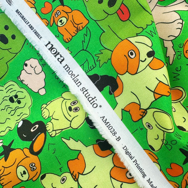 Selvage of Bow Wow Pop! cotton fabric in green by Nora featuring playful dogs on a green background, imported from Japan
