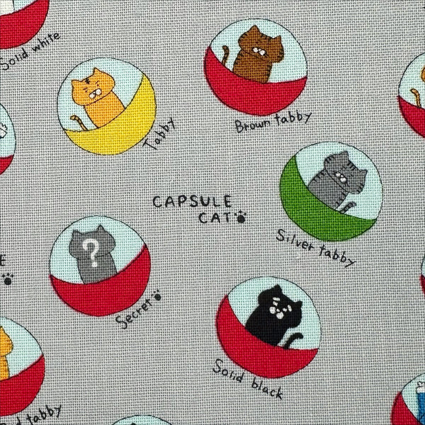 Close up of Capsule Toy Cats cotton canvas fabric in gray by Cotton Kobayashi featuring playful cats inside capsule toy machines on a gray background