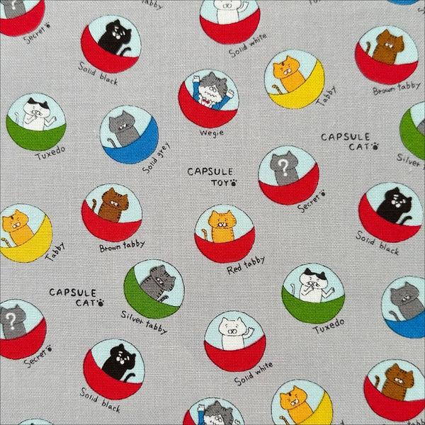 Capsule Toy Cats cotton canvas fabric in gray by Cotton Kobayashi featuring playful cats inside capsule toy machines on a gray background