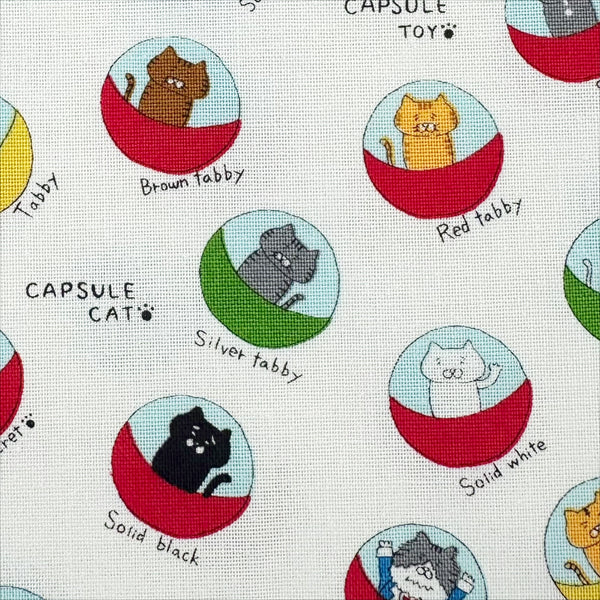 Close up of Capsule Toy Cats cotton canvas fabric in white by Cotton Kobayashi featuring playful cats inside capsule toy machines on a white background