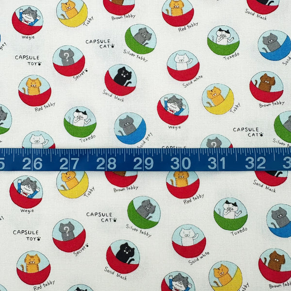 Scale of Capsule Toy Cats cotton canvas fabric in white by Cotton Kobayashi featuring playful cats inside capsule toy machines on a white background