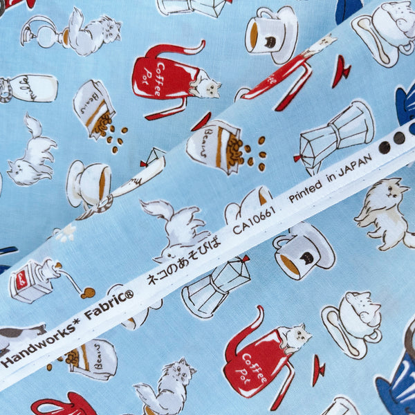 Selvage of Cat and Coffee cotton fabric by Handworks featuring playful cats and coffee-themed illustrations on a blue background