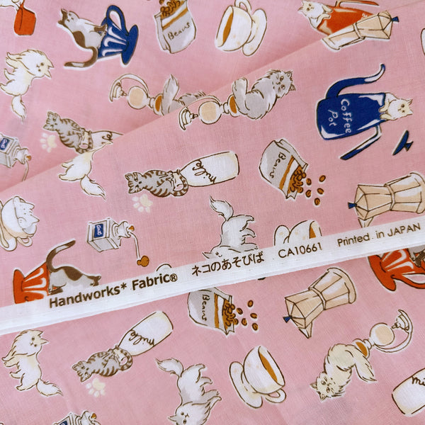 Selvage of Cat and Coffee cotton fabric by Handworks featuring playful cats and coffee-themed illustrations on a pink background