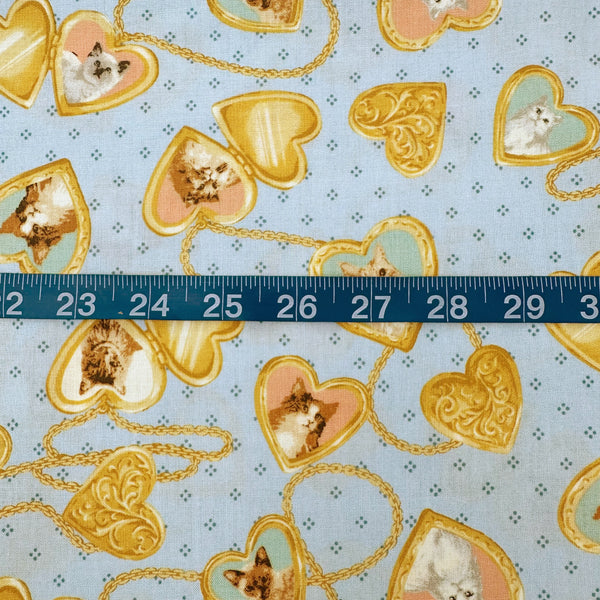 Scale of Cat Portrait Locket cotton fabric by Handworks featuring vintage-style cat portraits inside heart-shaped lockets on a blue background