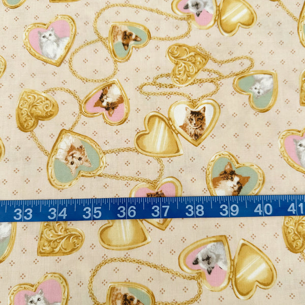 Scale of Cat Portrait Locket cotton fabric by Handworks featuring vintage-style cat portraits inside heart-shaped lockets on a tan background