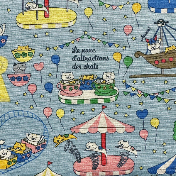 Close up of Catland Cotton Linen Canvas Fabric by Cotton Kobayashi, style KTS-7183C, featuring cats at an amusement park, in blue, imported from Japan
