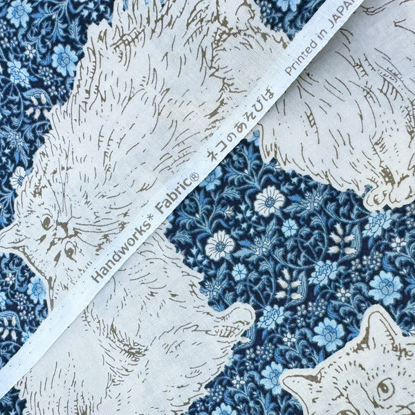 Selvage of Cats Playground cotton fabric in blue by Handworks Japan featuring large-scale cats on a petite floral background
