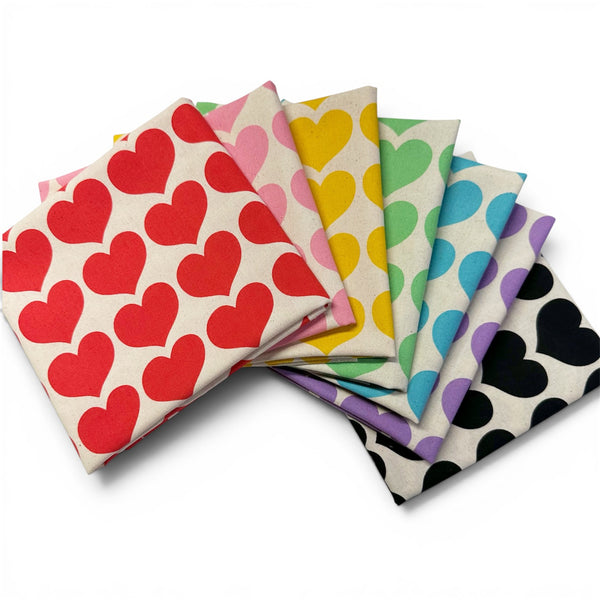 7 piece fat quarter bundle of Color Palette Hearts cotton fabric featuring red, pink, yellow, green, blue, purple, and black hearts on a natural cotton background