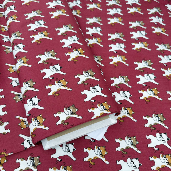 Bolt of Dancing Cats wine cotton oxford fabric featuring a repeating pattern of cat motifs on a wine background.