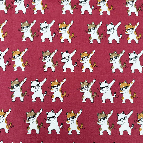 Dancing Cats wine cotton oxford fabric featuring a repeating pattern of cat motifs on a wine background.