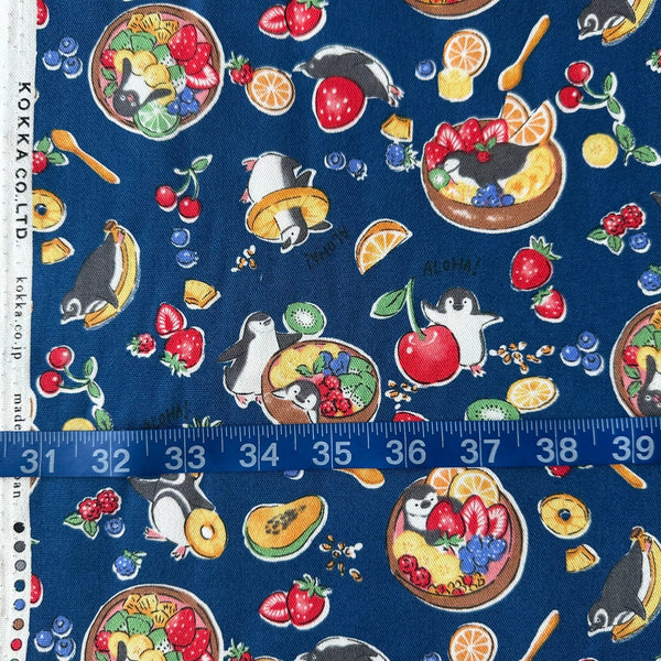 Delicious Animals Acai Bowl Penguin cotton oxford fabric by Kokka in blue, style YGA-91070-2D, shown with a tape measure for scale