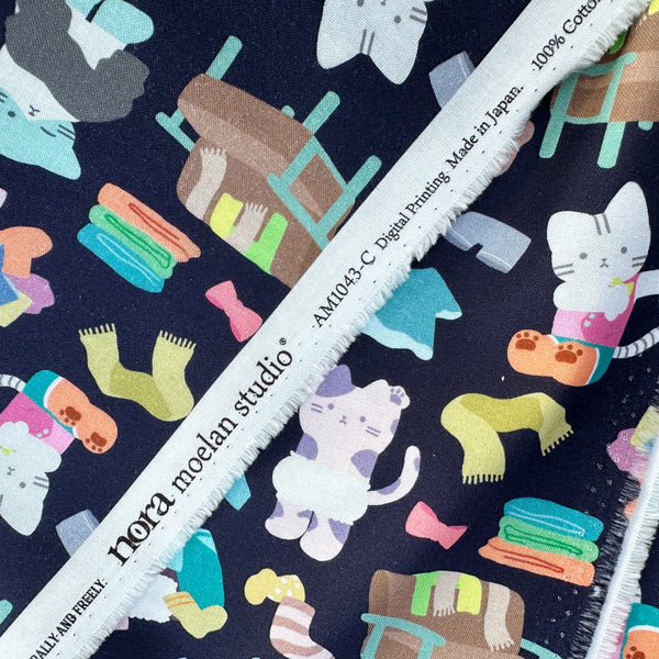 Selvage of Dressed Up Cats cotton fabric in midnight by Nora featuring cats with clothing and laundry illustrations imported from Japan