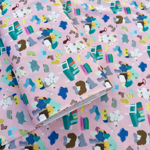 Bolt of Dressed Up Cats cotton fabric in pink by Nora featuring playful cats trying on outfits, surrounded by laundry piles and scattered clothes