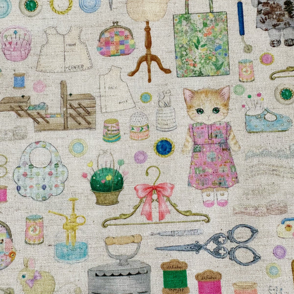 Close up of Dressmaker cotton linen fabric by Yukiemon for Hokkoh featuring delicately illustrated sewing notions, dressmaking tools, vintage sewing machines, and sweet bunny and kitty dressmakers on a natural background, imported from Japan