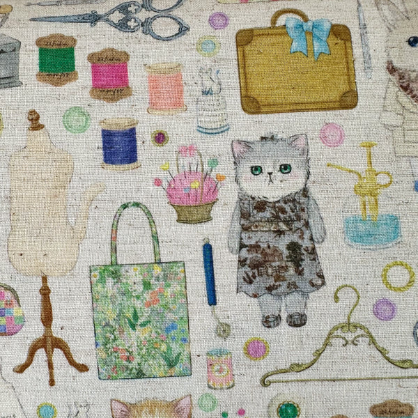 Kitty in Dressmaker cotton linen fabric by Yukiemon for Hokkoh featuring delicately illustrated sewing notions, dressmaking tools, vintage sewing machines, and sweet bunny and kitty dressmakers on a natural background, imported from Japan