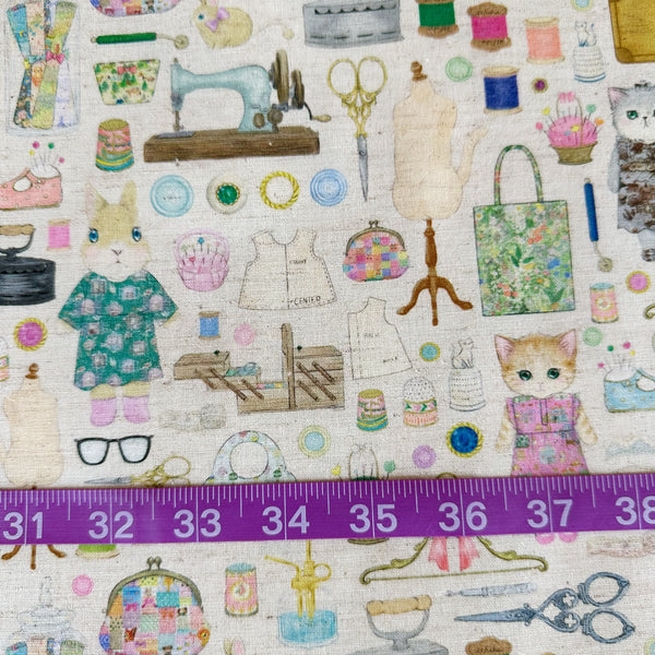 Scale of Dressmaker cotton linen fabric by Yukiemon for Hokkoh featuring delicately illustrated sewing notions, dressmaking tools, vintage sewing machines, and sweet bunny and kitty dressmakers on a natural background, imported from Japan
