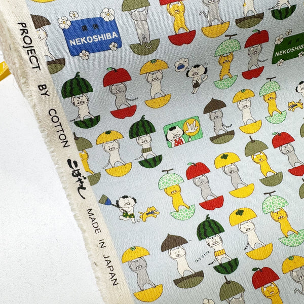 Selvage 0f Fruit Cats Canvas Fabric in Light Blue by Cotton Kobayashi – cats standing inside halved fruits on cotton linen canvas, imported from Japan