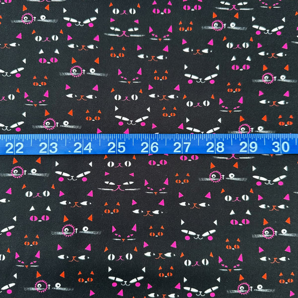 Scale of Hocus Pocus Pumpkin Patch cotton fabric by Helen Black featuring Halloween cat faces peeking through a shadowy black background