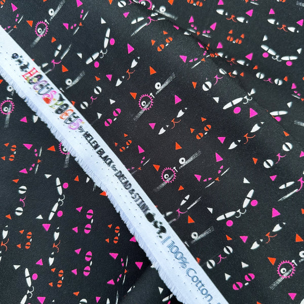 Selvage of Hocus Pocus Pumpkin Patch cotton fabric by Helen Black featuring Halloween cat faces peeking through a shadowy black background