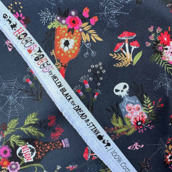 Selvage of Hocus Pocus Spellbound cotton fabric by Helen Black featuring potion bottles, spider webs, and mushrooms on a black background