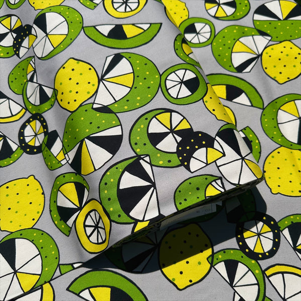 Bolt of Imported from Japan, cotton oxford fabric featuring a lemon and lime print in yellow and green on a gray background