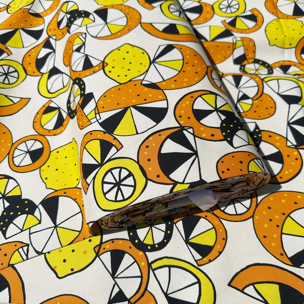 Bolt of cotton oxford fabric featuring a lemon and lime print in yellow and green on a natural background, Imported from Japan