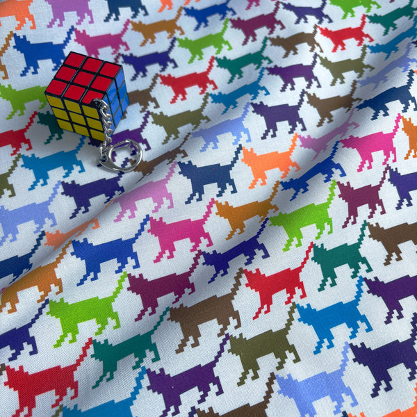 Stock photo of Meow Dot cotton fabric by Nora featuring a repeating pattern of multicolored pixelated cat silhouettes on a gray background, imported from Japan