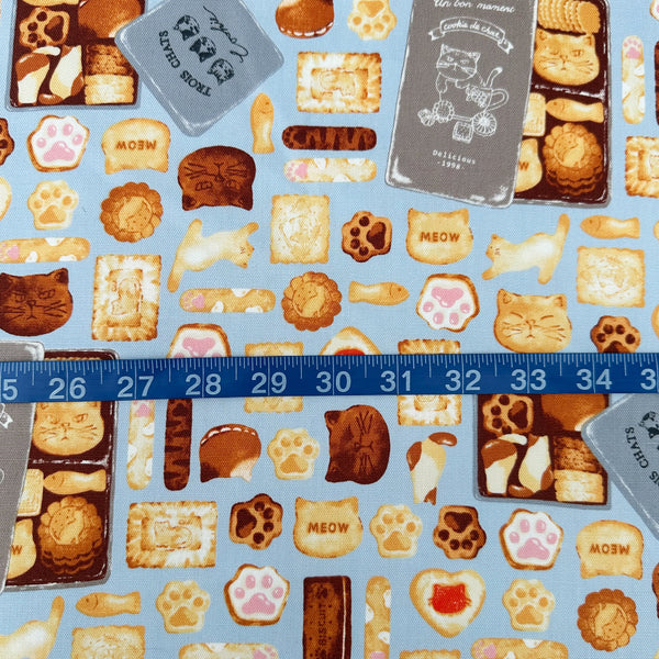 Scale of Neko Cookie Can cotton Oxford fabric by Komu Strada featuring cat-shaped cookies, biscuits, and cookie tins on a blue background