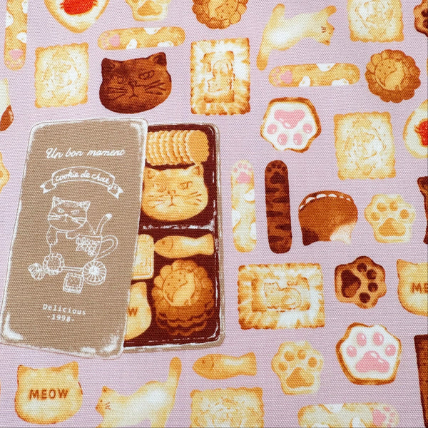 Close up of Neko Cookie Can cotton Oxford fabric by Komu Strada featuring cat-shaped cookies, biscuits, and cookie tins on a pink background