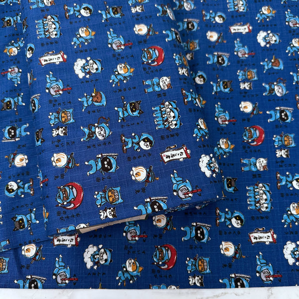 Bolt of Neko Ninja blue cotton dobby fabric by Cosmo Textiles, imported from Japan. Features playful ninja cats on a textured cotton fabric.