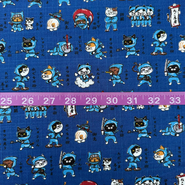 Scale of Neko Ninja blue cotton dobby fabric by Cosmo Textiles, imported from Japan. Features playful ninja cats on a textured cotton fabric.