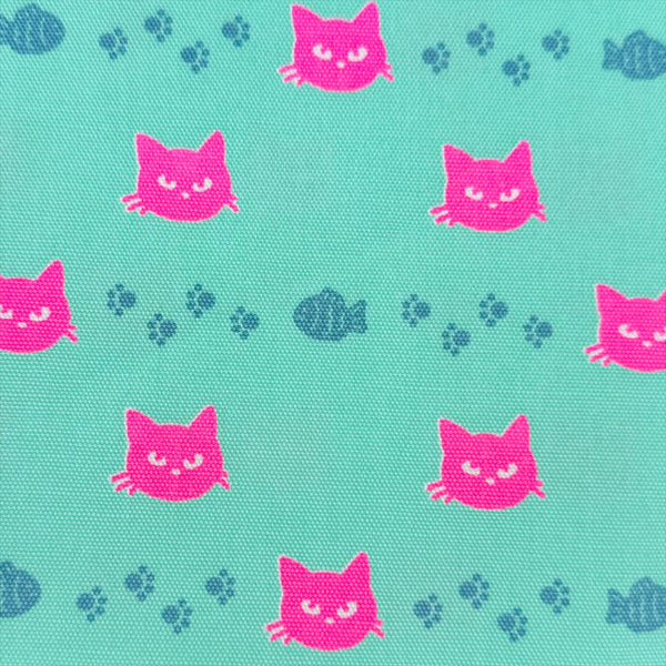 Close up of Neon Cat Cotton Oxford Fabric in Aqua featuring a playful print of fish, paws, and neon cat faces, imported from Japan.