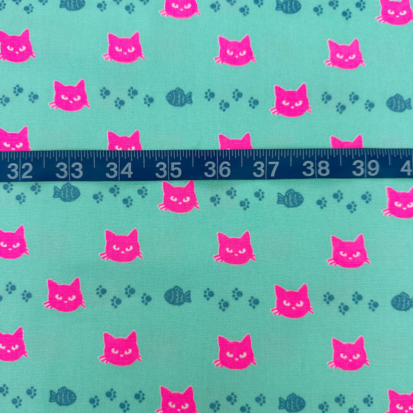 Scale of Neon Cat Cotton Oxford Fabric in Aqua featuring a playful print of fish, paws, and neon cat faces, imported from Japan.