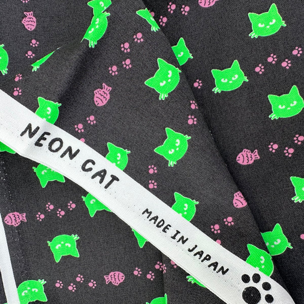 Selvage of Neon Cat Cotton Oxford Fabric in Charcoal featuring a playful print of fish, paws, and neon cat faces, imported from Japan.