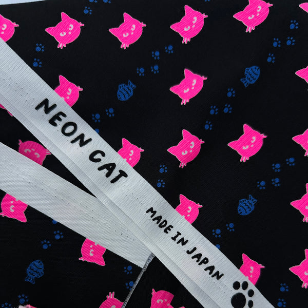 Selvage of Neon Cat Cotton Oxford Fabric in Black featuring a playful print of fish, paws, and neon cat faces, imported from Japan.