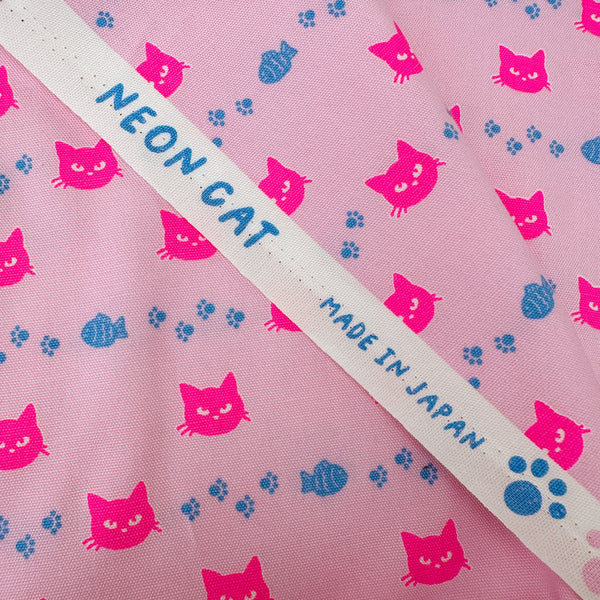 Selvage of Neon Cat Cotton Oxford Fabric in Pink featuring a playful print of fish, paws, and neon cat faces, imported from Japan.